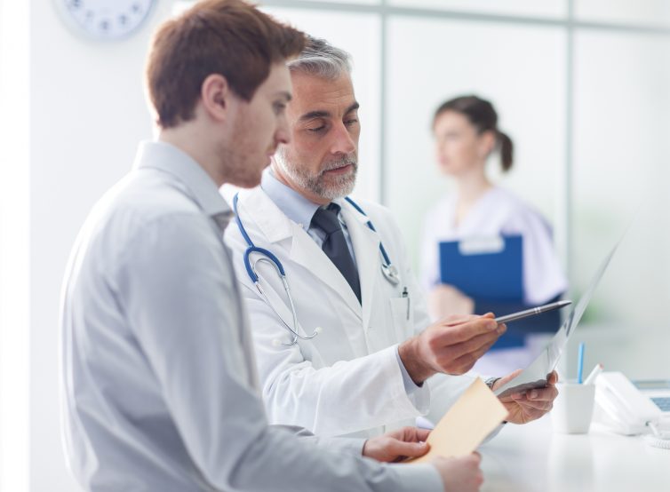 Doctor examining an x-ray and pointing, the patient is listening and watching, healthcare concept